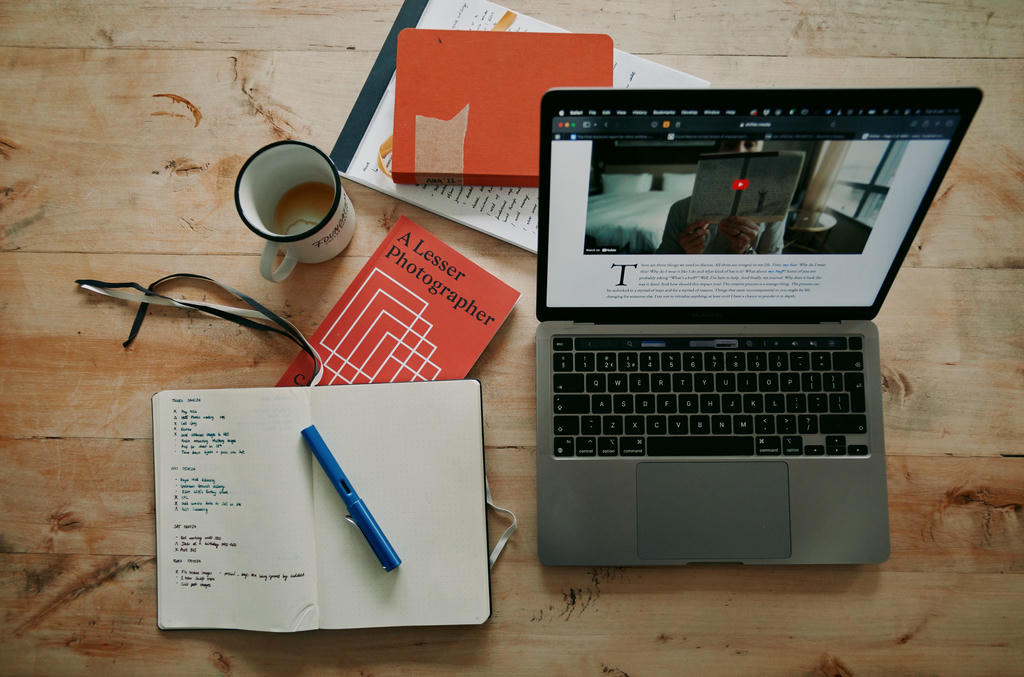 Collection of books, notepads and laptop on a wooden table