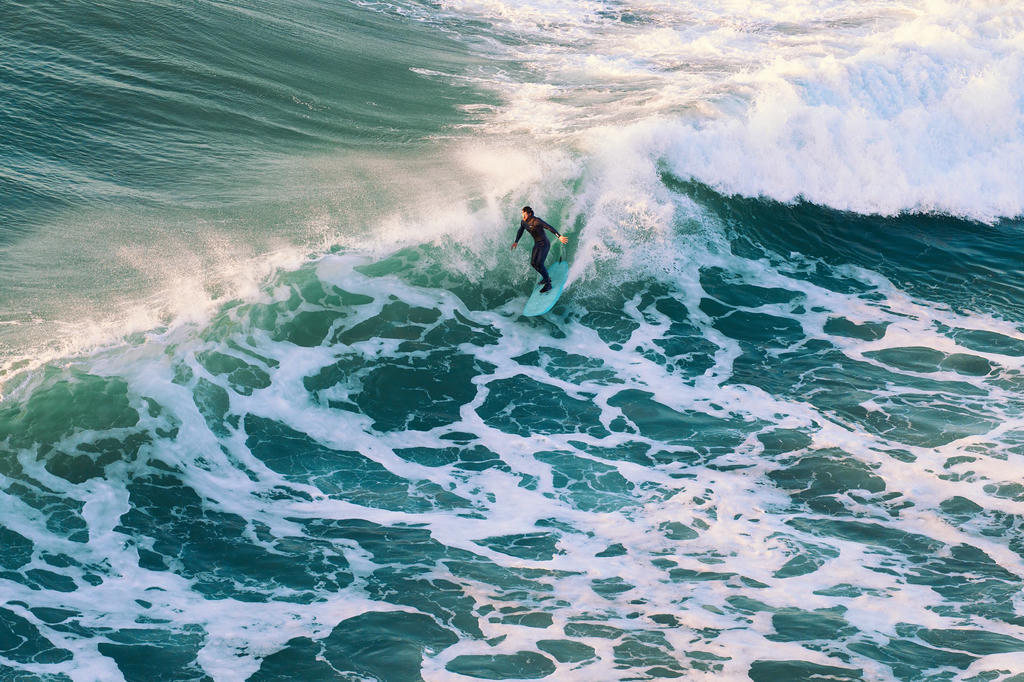 Surfer catching a wave in the sunset at Porthtowan, Cornwall