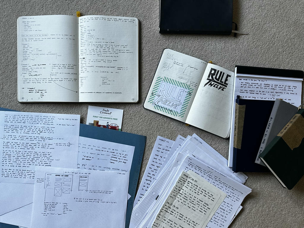 Various journals and notebooks strewn across the floor. Most with writing, some with sketches for app UI or logos